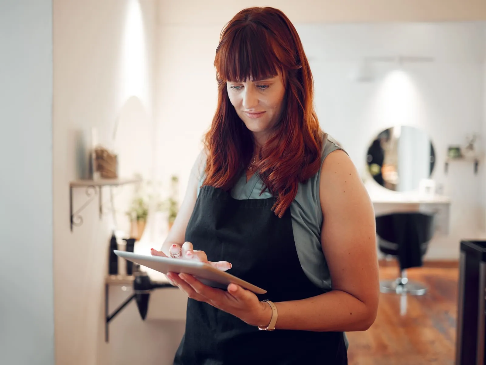 A salon owner checking bookings on a tablet in her hair salon